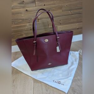 Coach Turnlock Tote bag in crossgrain leather and an oxblood or burgundy color. 